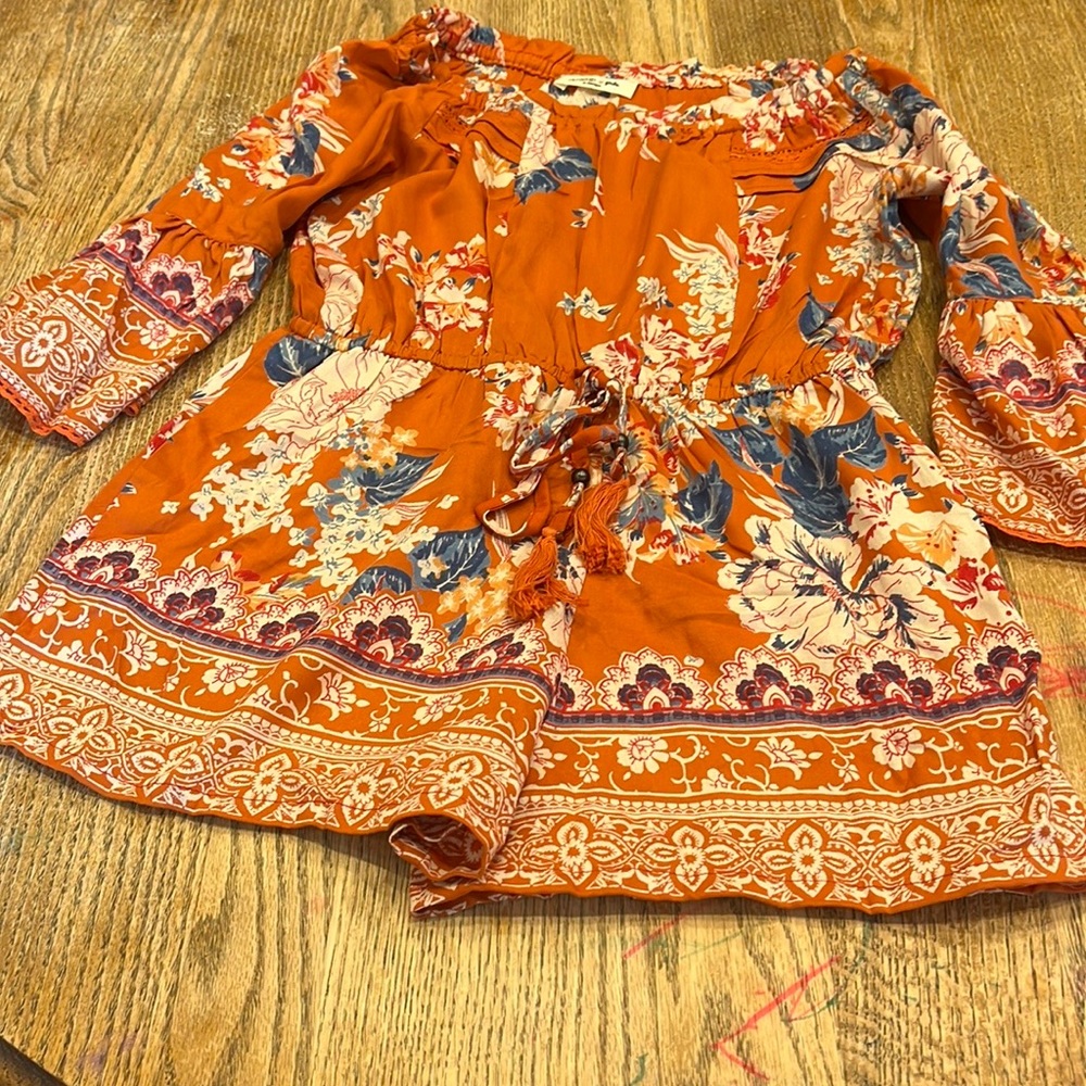 This is a deep rich orange color with beautiful floral patterns. It is a romper.